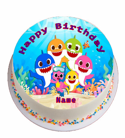 Round edible cake topper with cartoon shark characters and 'Happy Birthday' text .