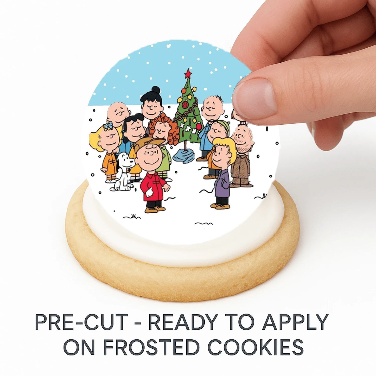 Charlie Brown Cookie with a Christmas-themed Edible Cake Image design and a hand holding a pre-cut decoration above it.