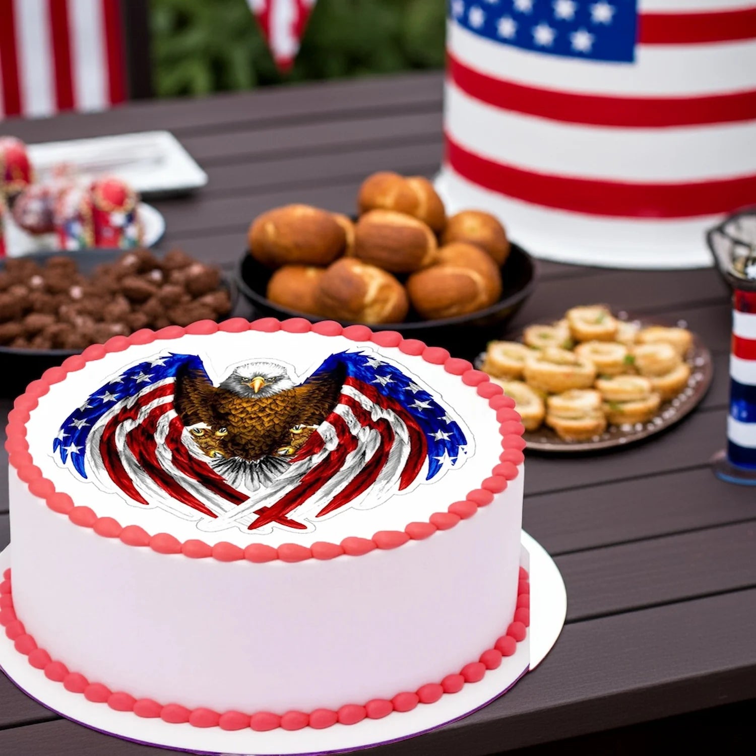 Patriotc & Military edible image cake topper on a picnic table surronded by Holidays or birthday decoration.  The cake showcases an eagle with red white and blue flag wings.