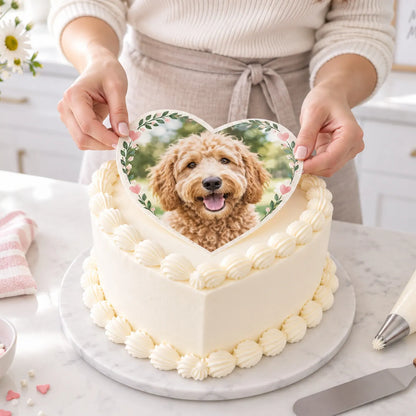 Hands placing precut custom photo heart edible icing sheet onto a heart shaped cake